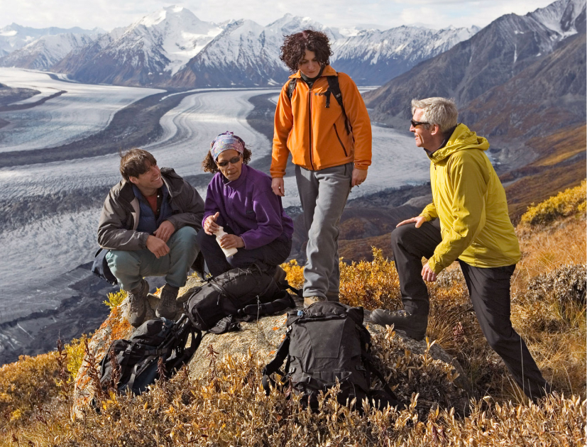 Outdoor adventurer using a premium survival gear kit with hiking backpack and camping tents in a mountain setting