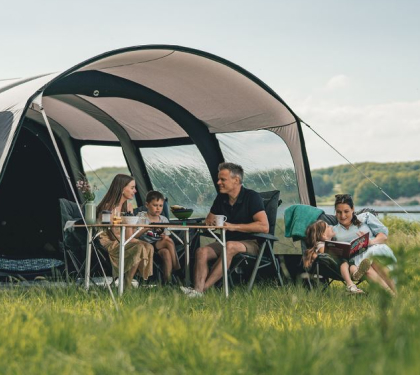 Outdoor hiking tent set up in the wilderness with a complete survival gear kit, hiking backpack, camping shovel, and cold weather sleeping bags